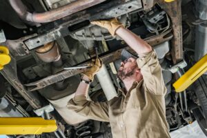 Car Mechanic Performing Undercarriage Repair